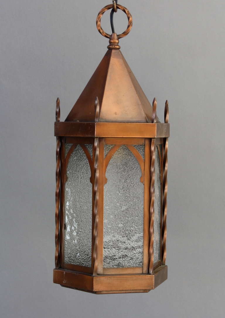 Peirod brass lantern lined with textured glass panes behind gothic arches.