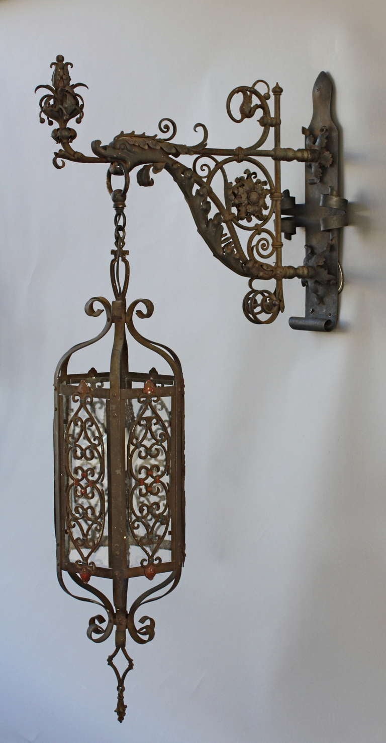 Finely hand-wrought iron pendant light. The ironwork is exceptional and is a fine example of the Spanish Revival movement. The dragon head is incredibly rendered.  The lantern retains its original polychrome patina.