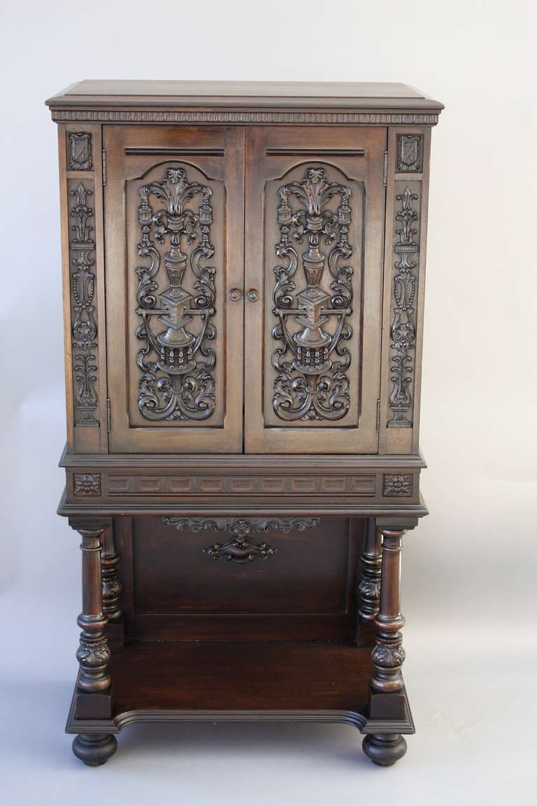 Striking cabinet with rich, dark finish and ornately carved face; doors open to reveal a pullout writing desk, drawers and postal files