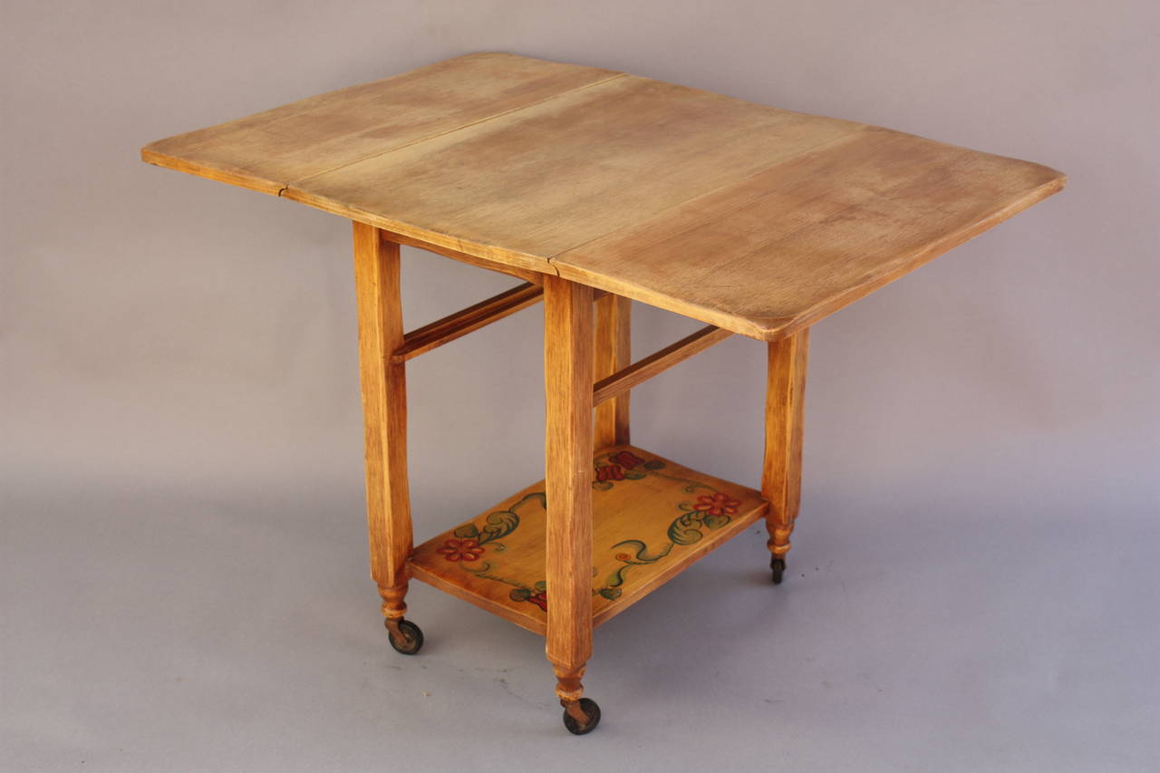 Circa 1930's. Hand painted Coronado folding serving table on wheel. Some wear on top but great vibrant hand painted detail on lower tray. Closed the width is 17.75