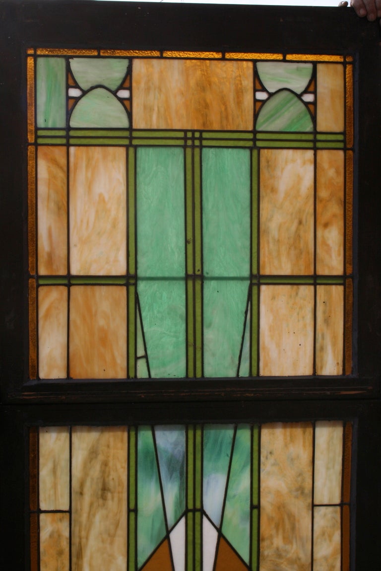 Large and dramatic art glass windows c. 1910 comprised of slag glass in shades of marbled green and ochre intricately leaded in geometric patterns; priced and sold separately, measurements below are for one of the two windows available