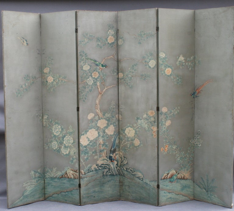 Intricately hand-painted silver leaf 6-panel screen features several colorful birds amongst blossoming tree branches. Entirely hand-painted with fine attention to detail, this is a stunning piece rendered in a quiet and lovely color palette.