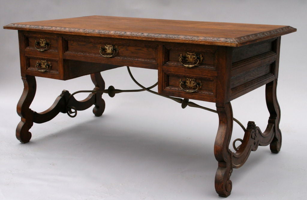 Classic style Spanish Revival desk with wrought iron stretchers.  It features five deep drawers with nicely detailed carving.