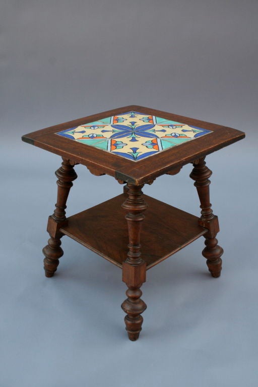 Stately designed table with heavy turned legs and a single shelf.  It features a four tile pattern with Tudor California tiles.