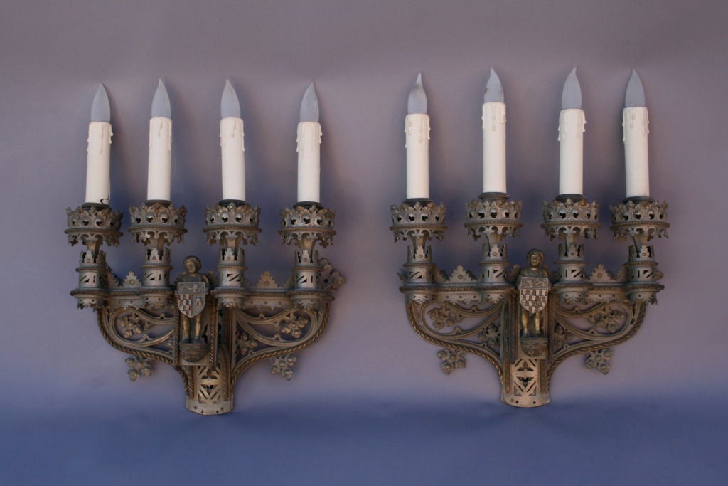 Extremely detailed four-light sconces from a grand Los Angeles area estate; intricate cast details abound including figures mounted at front, crests, fleur-de-lys, and many ornate cut-outs; finish is original.