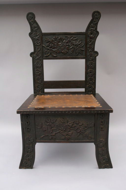 Beautifully carved in a highly detailed floral design with wide seat upholstered in leather.