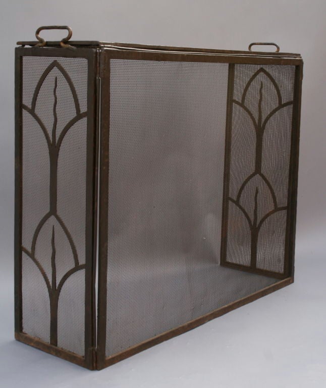 Hand-wrought free-standing screen  features stylized calla lily motif at side panels of an otherwise simple design. This unique screen is hinged at both sides as well as across top panel top, making it easy to attend to fire, while fully enclosing