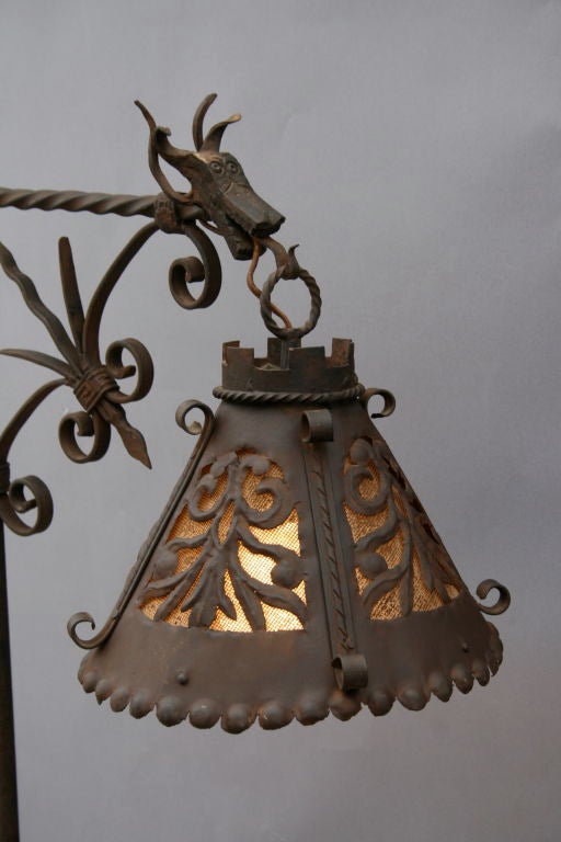 Wonderfully hand-wrought lamp displaying all the whimsical beauty and craftsmanship of 1920's ironwork, much like the work of Samuel Yellin; original shade of repousse cutwork over mesh is suspended from dragon's tongue