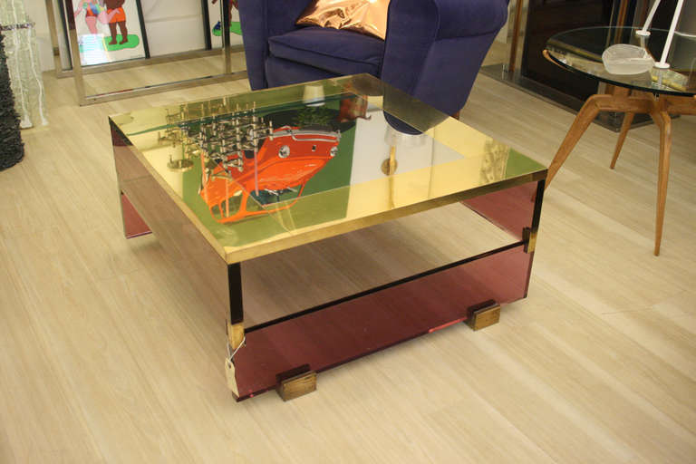 A 1970s occasional  coffee table, brass metal top on a pink perspex base with brass feet. design by Romeo Rega.
