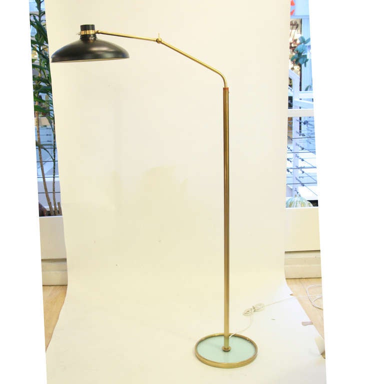 A floor light, brass structure, glass base black enameled shade, adjustable heights, movable shade. Design Gio Ponti for Fontana Arte, circa 1960.