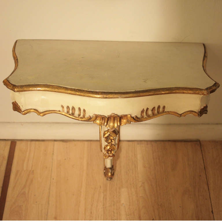 A pair of carved wood consoles, cream color painted wood with gold color details. Italian Design.