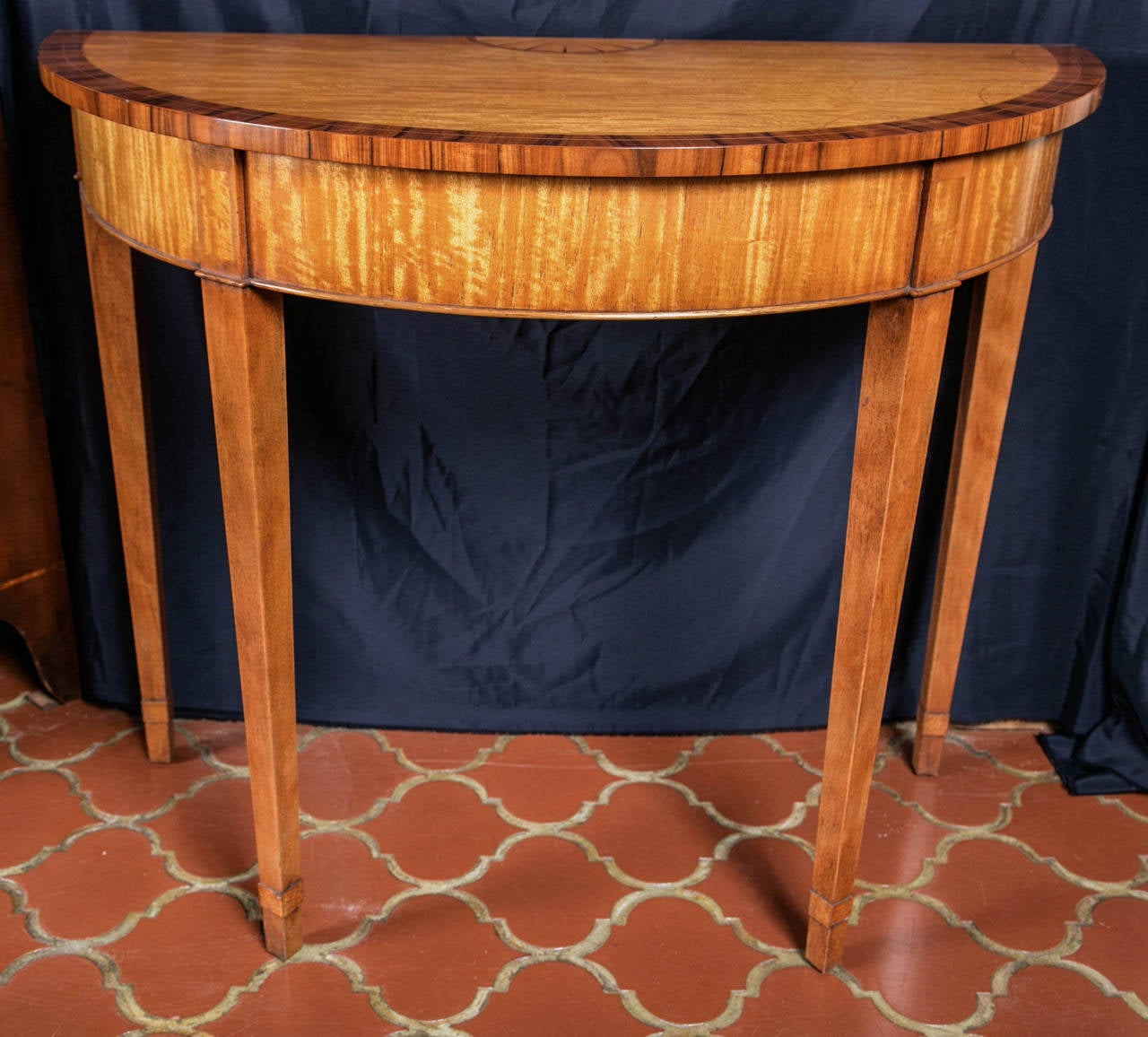 Handmade for us by our English craftsmen, this little demilune / console shines with the reflective qualities inherent in satinwood. Light dances off the grain and gives the surface a rich, satiny look that allows it to ably cross stylistic