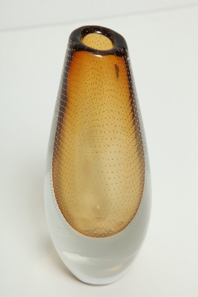 Gunnel Nyman hand blown amber colored glass vase with internal controlled bubbles cased in clear glass made by Nuutajärvi, Finland. Signed.