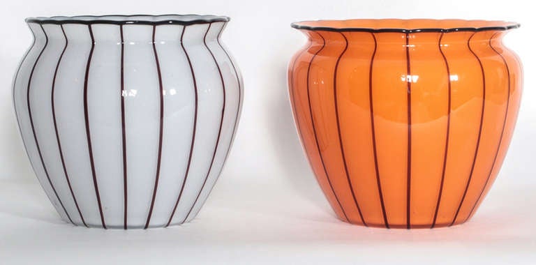 Pair of Michael Powolny vases made by Loetz. One of tango orange tone with vertical black lines and rim. The other a translucent white tone with vertical black lines and rim. Both vases have a slightly concave base with ground and polished pontils.