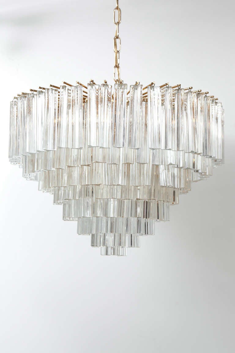 Vintage Murano glass chandelier composed of 8 tiers of hand blown triedre crystal prisms. The polished brass plated frame has 6 lights, rewired to US standards. This chandelier is new/old stock and has never been used outside of a lighting showroom.