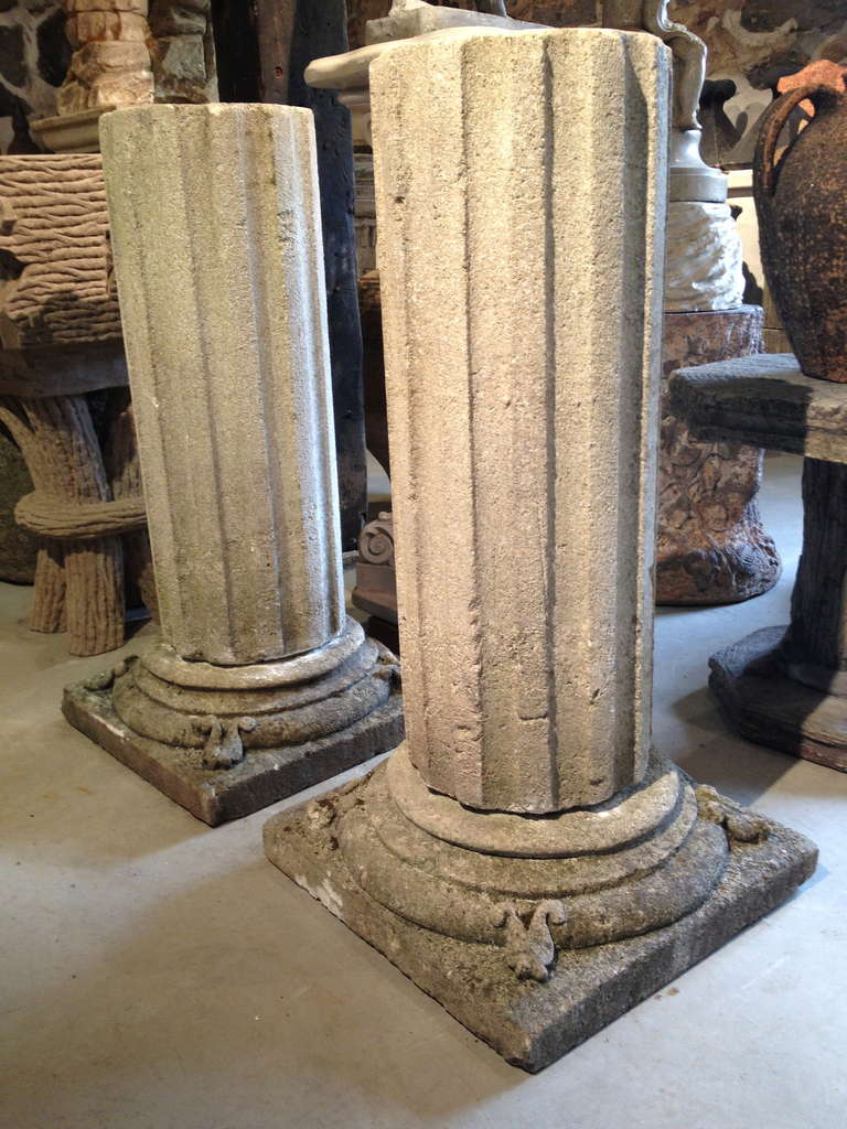 This is a stunning pair of fluted hand-caved limestone columns, each in two parts, with unusual decoration to the bases.  Wonderful as pedestals to display a pair of urns or, we can trim them to your specifications to make bases for a stone-topped