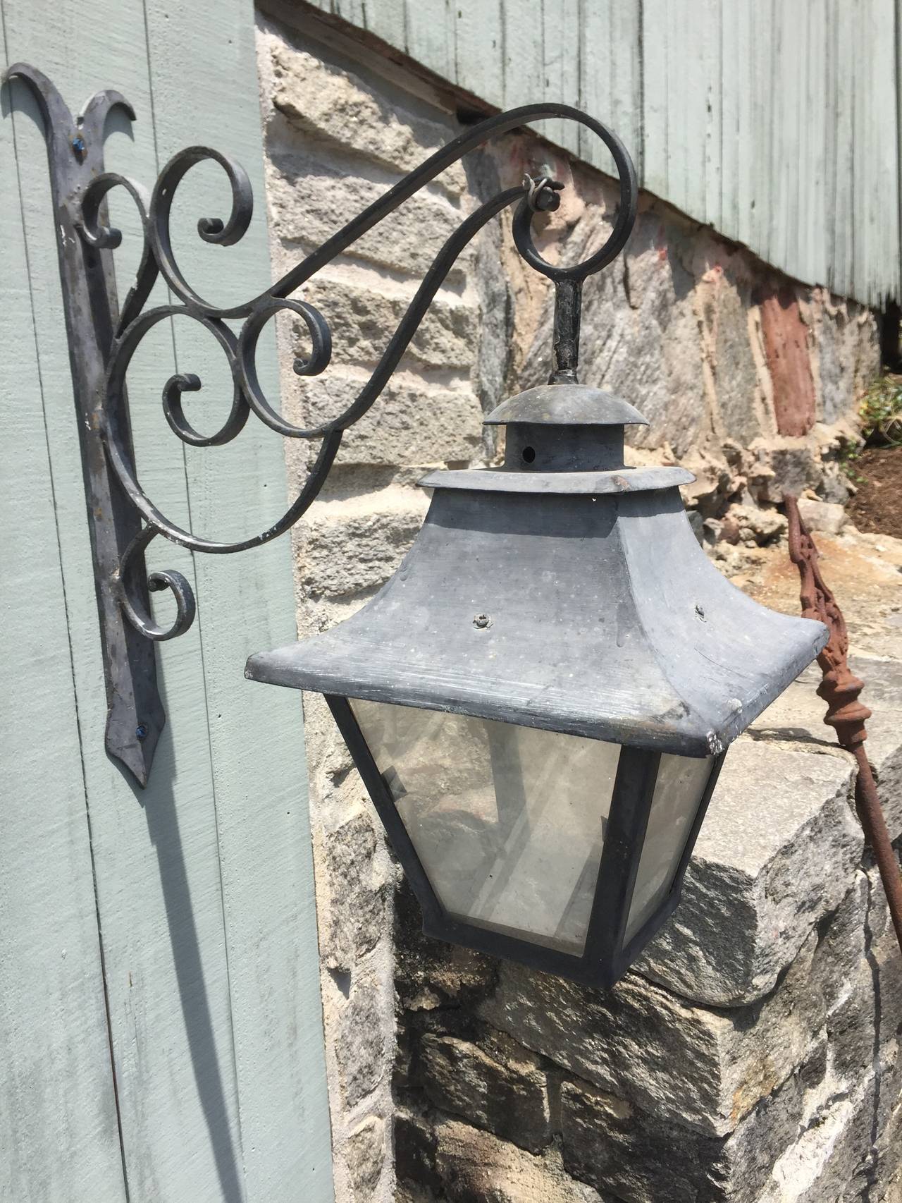 We bought this wonderful lantern in the Southwest of France, not far from Bordeaux. Made of wrought iron and steel, with its original scrolled bracket and attachment plate, the old paint has weathered to a lovely grey that looks like zinc. It would