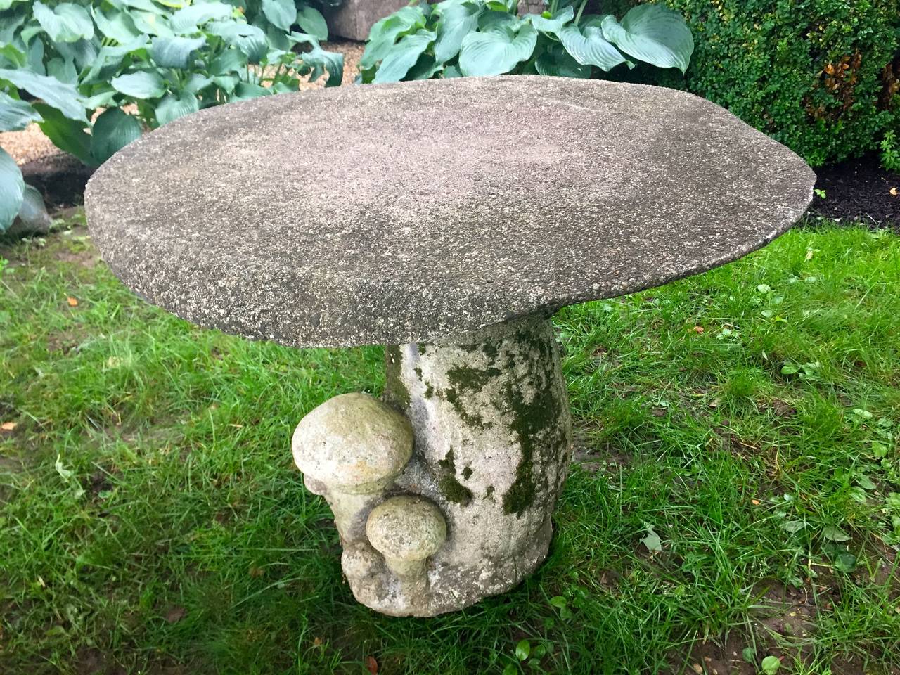 This set is really amazing and all original! Made of cast stone, the realistic table is loaded with lichen and moss, features a cluster of small toadstools on the base, and has downward-curving edges. The four matching stools are each a little