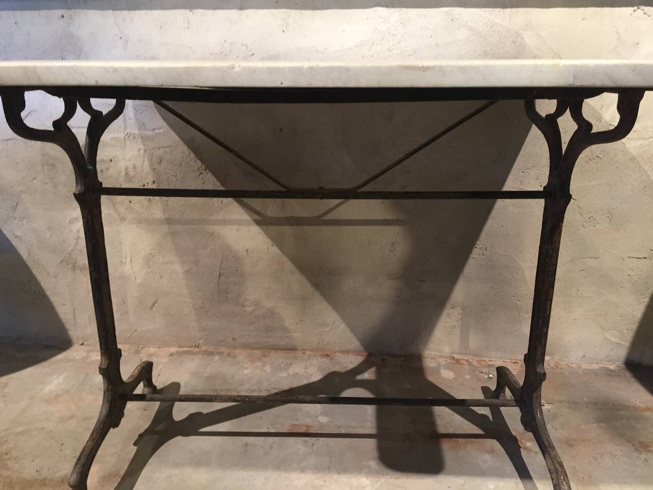 This classic Art Nouveau cast iron table features its original cream-colored marble top and is signed 