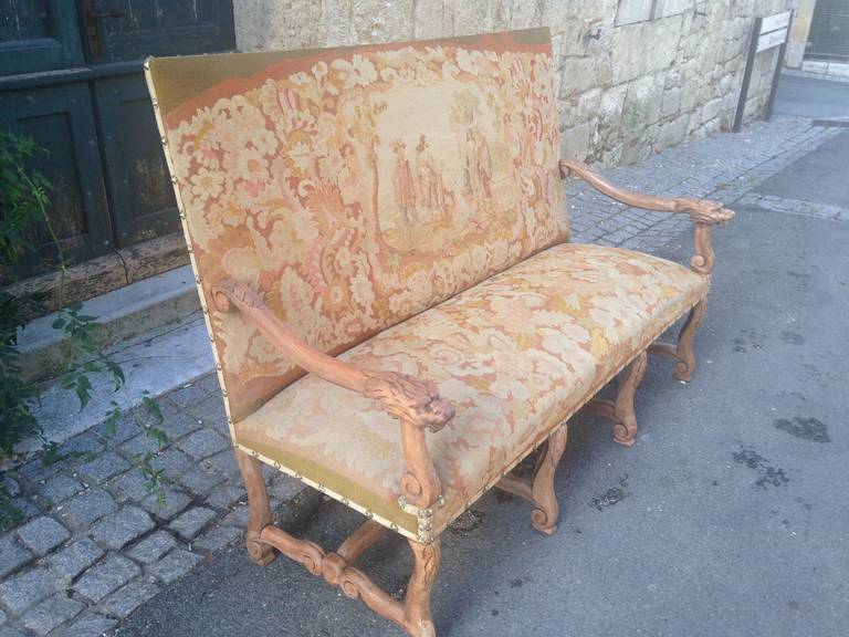 This stunning, large and very comfortable hand-carved walnut banquette/sofa sports its original needlework tapestry upholstery featuring the Three Mousquetieres, d'Artagnan and the Queen of France. The needlework is in near-perfect condition and has