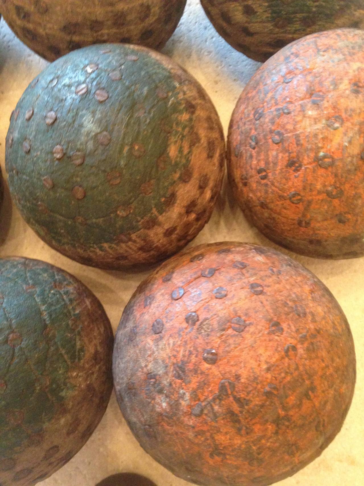 This is a very rare and complete set of boules, featuring the little target one, as well as four half painted in dark green and four in a salmon color. The boules themselves are hand-carved and studded with original 19th century nails. Used to play
