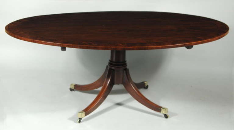Very fine late George III inlaid figured mahogany oval top dining or breakfast table, with superbly figured solid mahogany top with sectioned deep mahogany crossbanded and string inlaid edge, tipping on a cannon shaft column raised on four string
