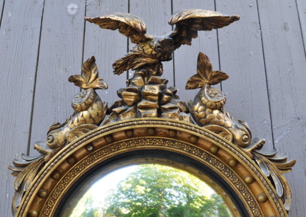 Very fine classical regency style convex girondole mirror, with eagle surmount above a rockery flanked by facing dolphins, the circular frame with impressed floral detail and cove molding with round spherules, flanked by two pair of scrolled foliate