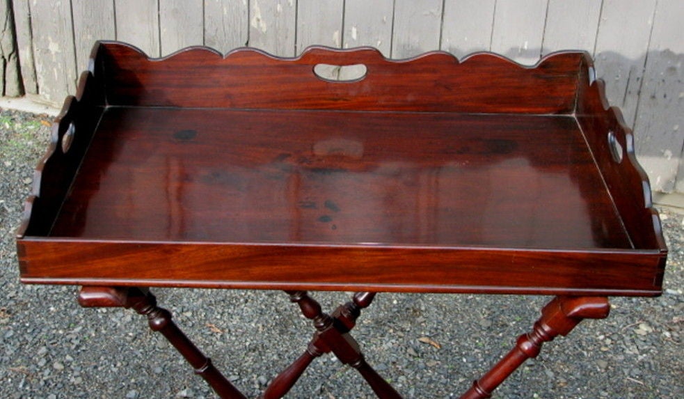 Exceptional Regency carved mahogany butler tray on folding stand, with wonderful scalloped top edge and cutout handles, with folding stand having multiple baluster turned elements ending in turned stump feet. England, early 19th century.