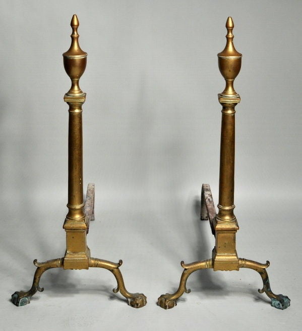 Very fine pair of Chippendale brass andirons with arched, double spurred cabriole legs with double collar and vigorous sculpted claw and ball feet, supporting a plinth with scalloped base and shafts of columnar form having urn form finials.