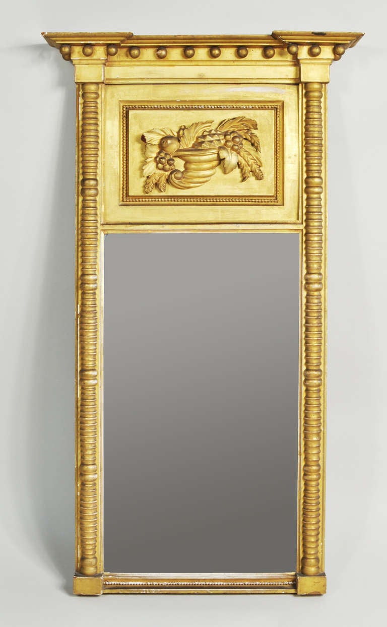 Fine Sheraton early classical carved giltwood tabernacle mirror, with cove molded cornice with gilt spherules, above a leaf carved tablet and an original mirror glass, flanked by spiral carved columns. Probably Boston area, circa 1815-20.