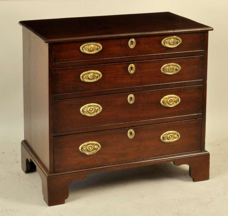 Very fine diminutive George III figured mahogany bachelor chest, with molded top above four beaded graduated drawers, set on bold cutout bracket feet, retaining rich original colour and foliate oval brasses. England, circa 1770-80.