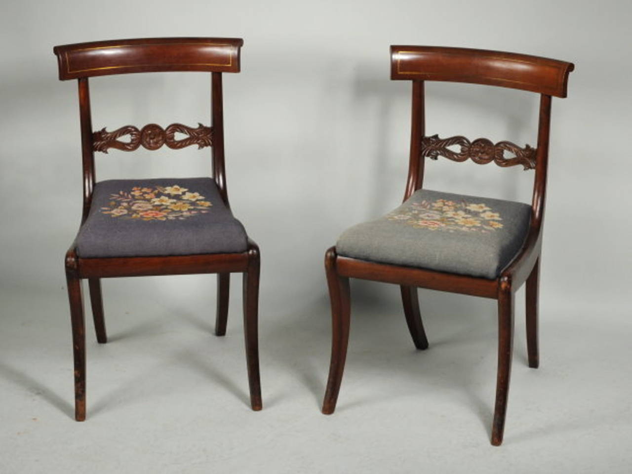 Fine pair of carved and brass inlaid mahogany side chairs with
curved and rolled crest rails with brass string inlay, set on stiles centering a carved horizontal splat with carved central boss and leafage, with slip seats raised on shaped sabre