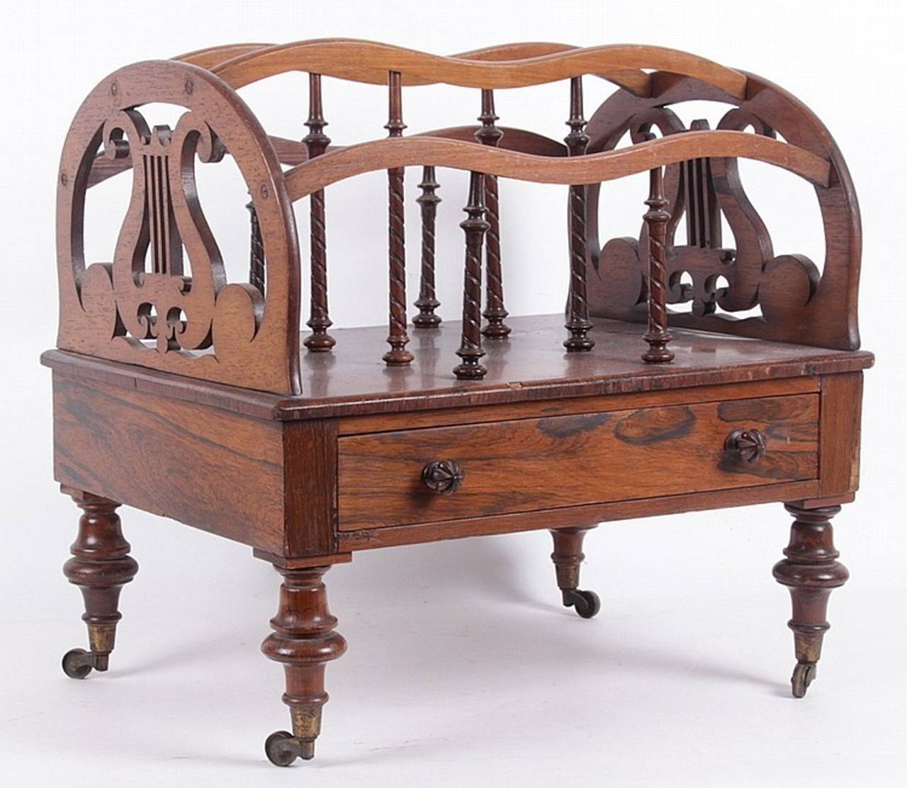 Fine Regency rosewood canterbury, with arched lyre ends with
undulating strap dividers with rope turned supports, above one working drawer, set on turned legs ending in original brass cup casters. A very successful form and retaining rich mellow