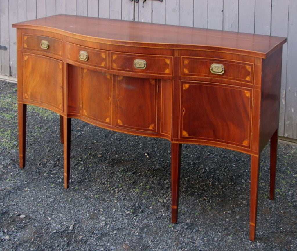 Very fine Hepplewhite style inlaid mahogany serpentine sideboard, with conforming top with inlaid upper and lower edge, above a case with matchstick inlays above one bowed central drawer and two flanking concave end drawers, above a recenssed center
