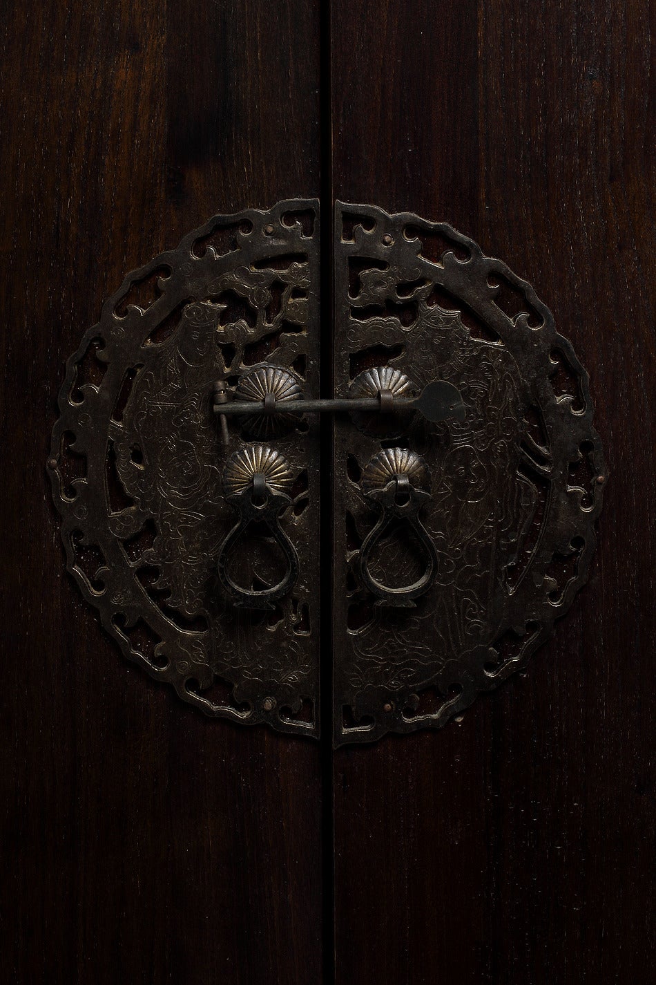 A dark lacquer Chinese wedding cabinet from the 1800s. This Chinese 19th century wedding cabinet is made of dark lacquered wood and bronze hardware. This cabinet showcases a simple shape with an overhanging top and round corners. The legs are