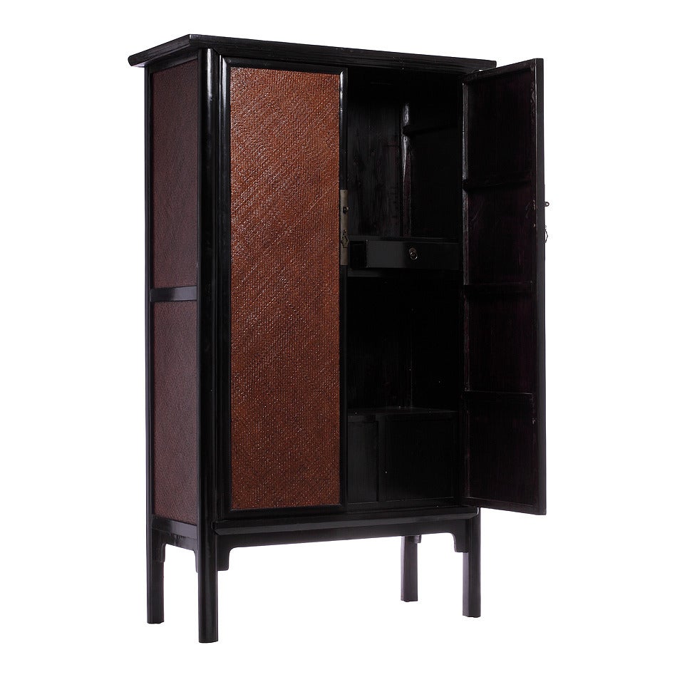 A Chinese armoire from the 1800s with rattan panels and black lacquer. This Chinese armoire was made with black lacquered wood and rattan panels. The armoire adopts a refined rectangular shape with a black lacquered wood structure and a black