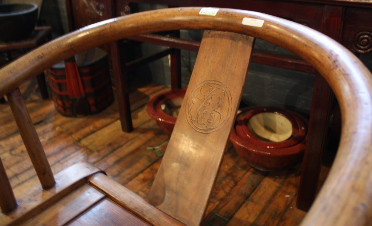 A petite 19th century Chinese country style elm side chair. Featuring a curved shape and a bow back, the chair showcases a solid seat raised on four large straight legs connected to one another by side stretchers. The seat rail is adorned with a