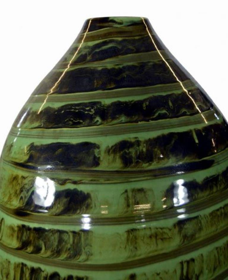 A large Thai 20th century vase made with high fire incised ceramic covered with green glaze. This vase adopts an olive shape with a narrow neck and is adorned with a green glaze spiral mixed with dark brown glaze. This dynamic abstract pattern is