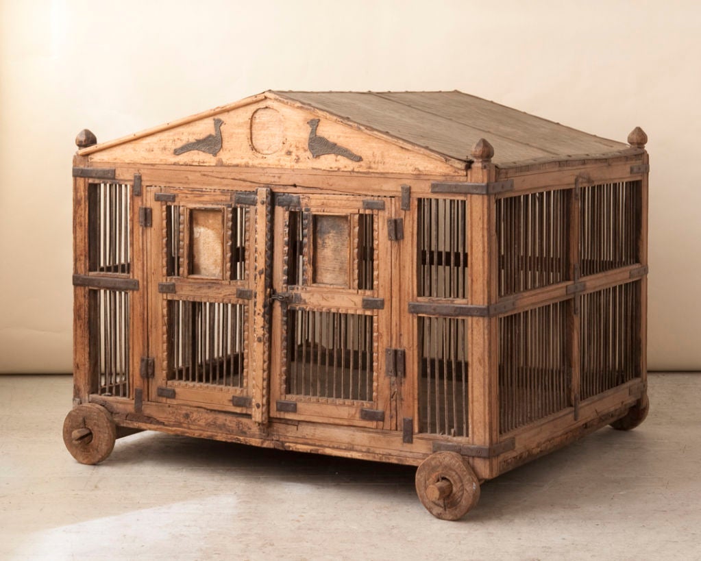 A large antique Asian wood and iron bird cage, with a quilted metal roof,  in the form of a house on 4 wooden wheels  <br />
Width-36 3/4
