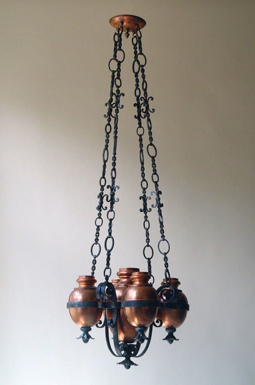 An unusual Arts and Crafts hanging fixture with copper urns suspended in iron with a decorative iron chain, Continental, late 19th century, not wired. <br />
Height w. chain 57