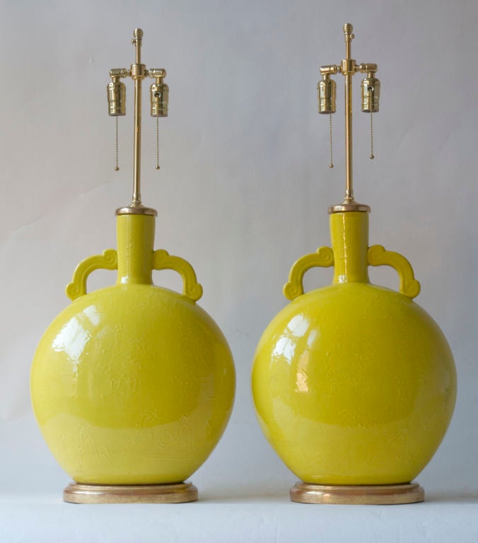 A pair of moon shaped flattened bottle form Chinese porcelain vases, yellow glazed with raised decoration, bottle neck with handles, with giltwood tops and bases, mounted as lamps