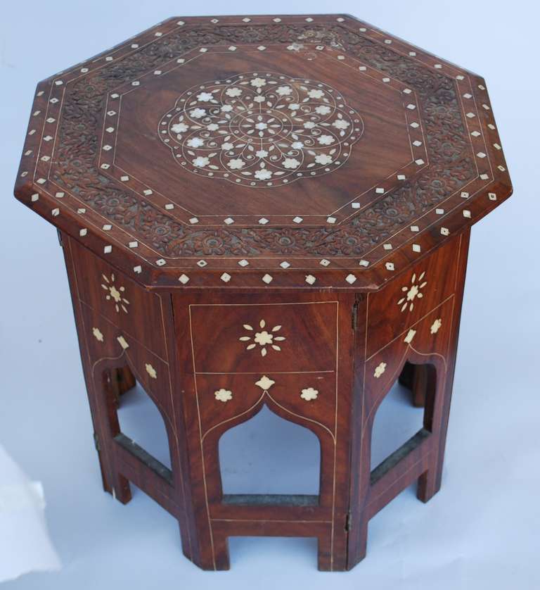 Lovely folding Anglo Indian folding table. Very attractive inlay design with intricate carved design elements on top.