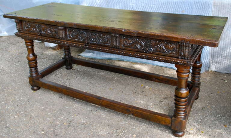 Incredible 17th Century Spanish console table. It is composed of solid Walnut with a single plank top. The piece is carved throughout, including the backside and can float in a room. The drawers are carved with grape leaves and vines. Original iron