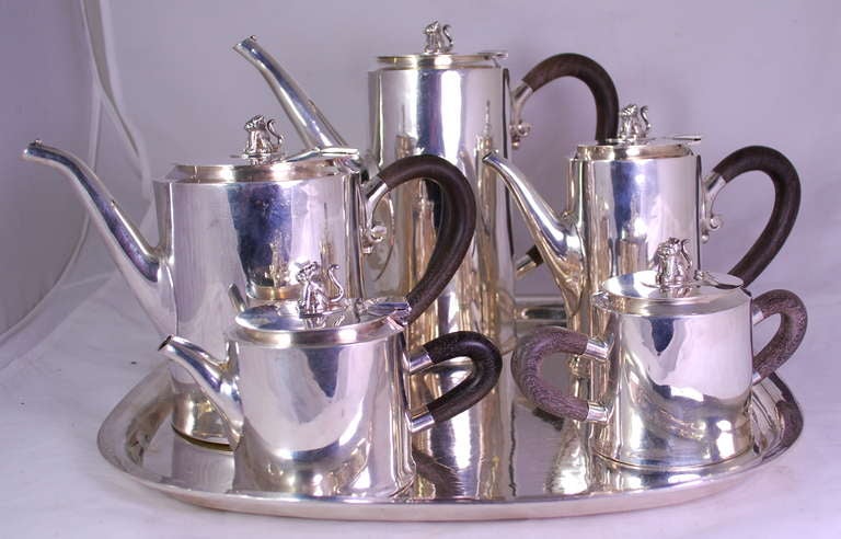 A MEXICAN SILVER FIVE-PIECE TEA AND COFFEE SERVICE WITH TRAY** 
MARK OF WILLIAM SPRATLING, TAXCO, 1947-67 
Comprising: a teapot, coffee pot, hot milk pot, sugar bowl and cream jug; each cylindrical, with wood handles, the covers surmounted with