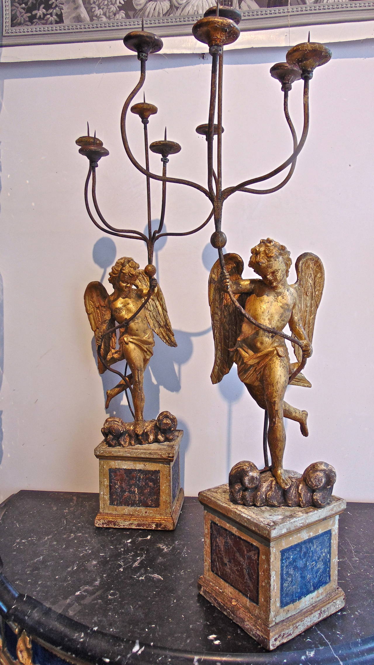 Period Italian Baroque carved and parcel gilt candelabra.

--Gilt and faux marble wooden candelabra.
--Realistic putti or angels holding pricket candle arms.
--Faux lapis and porphyry.