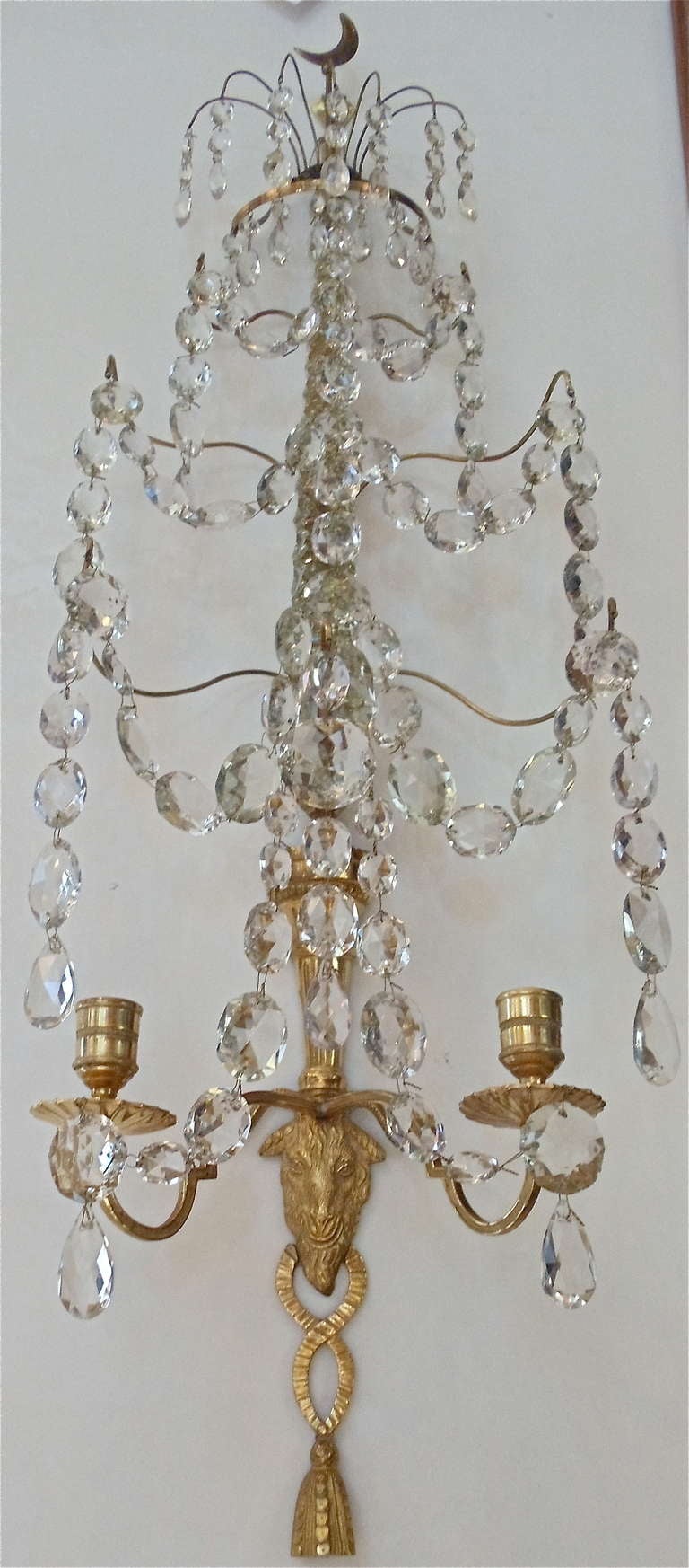 Pair of Late 18th Century Russian Neoclassical Ormolu and Cut Glass Sconces

--Each with a cut glass spire fitted with gilt bronze sprays linked by chains of faceted drops and suspending faceted pendants, the lower part with a ram's head flanked