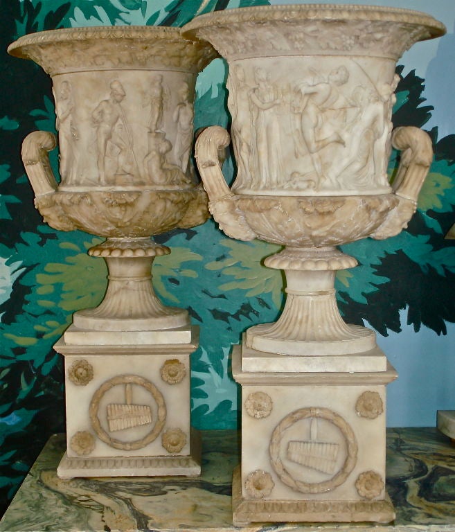 Pair of Early 19th Century Alabaster Urn of the Medici Form.  These Campana shaped urn bears a carved relief depicting the legend of Iphigenia. The flared rim has egg, dart and bead mouldings, while the leaf carved, scrolled handles are supported by