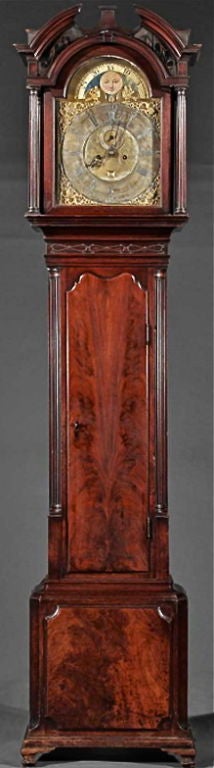 Exquisitely Figured and Bookmatched Mahogany Tallcase Clock with Moon Phase Works and Intricate Brass Spandrels.