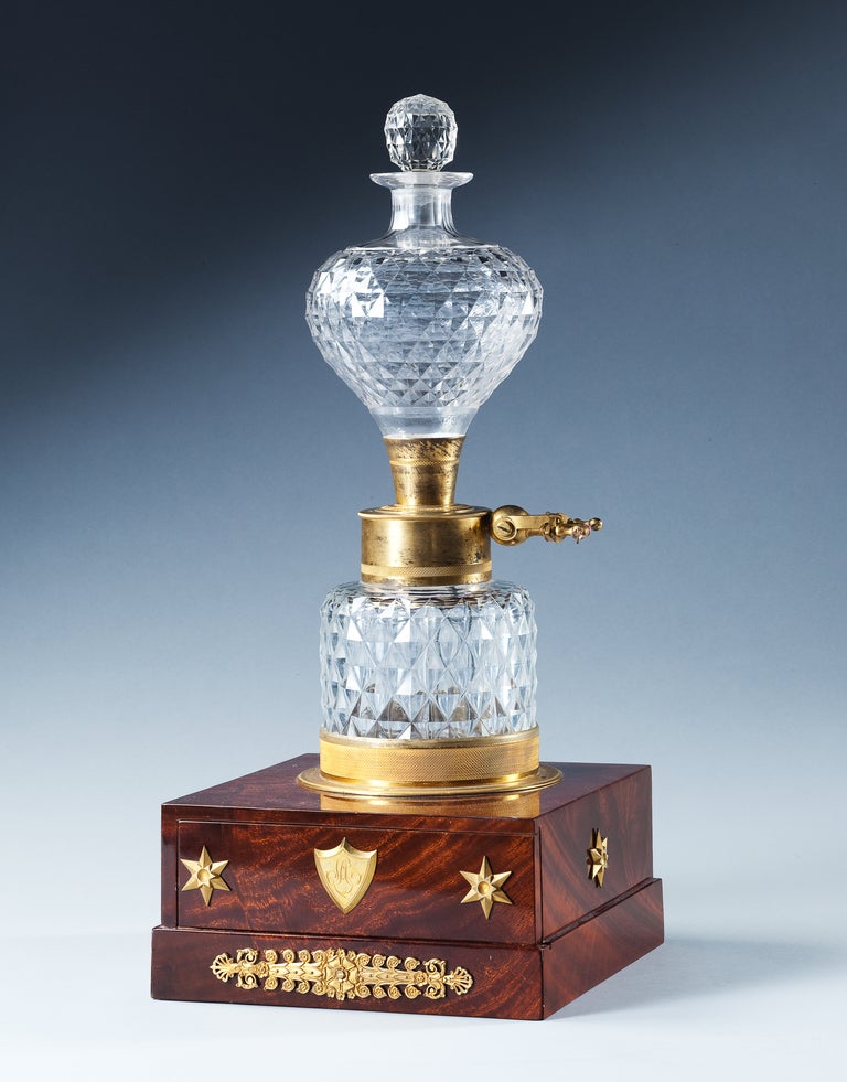 A highly unusual early 19th century volta-electric lighter consisting of two cut glass jars with central steel and copper ignition switch. The upper-vase with original stopper is supported on a mahogany pedestal decorated with gilt-metal mounts with