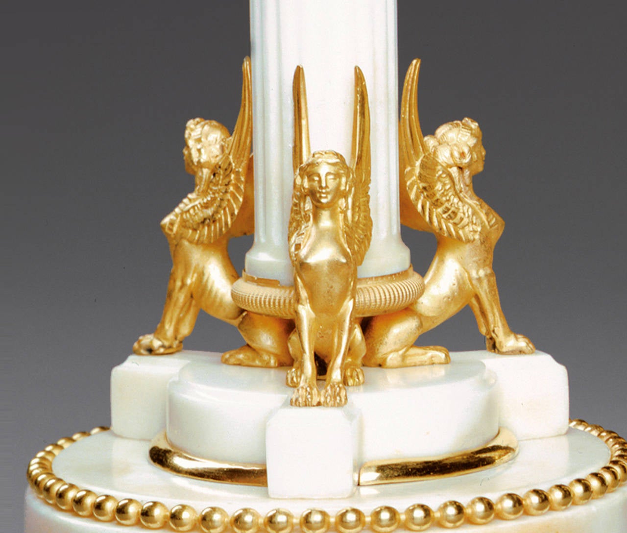 A pair of Empire period Swedish white marble and metal candlesticks. They stand on a tripod plinth, which in turn rests upon a circular plinth with a gilt beaded border, which terminates in gilt bun feet also with a band of beading.